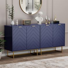 a blue sideboard with gold accents and a round mirror on the wall above it