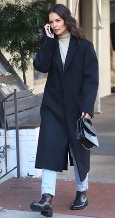 a woman is talking on her cell phone while walking down the street with a handbag