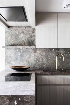 a modern kitchen with marble counter tops and stainless steel appliances, along with an oval bowl sink