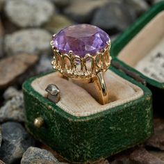 This amethyst cocktail ring features a round cut amethyst in an ornate four prong setting. It is crafted in 14k yellow gold and currently sized to a 5.5. The amethyst shows light wear but it does not distract from the beauty. Amethyst Cocktail Ring, Brand Presentation, Old Boxes, Show Lights, October Birth Stone, Cocktail Ring, High Quality Jewelry, Cocktail Rings, Estate Jewelry