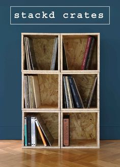 a wooden book shelf filled with books on top of a hard wood floor next to a blue wall