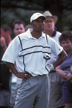 a man standing in front of a crowd with his hands on his hips while holding a golf club