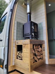 a van is loaded with wood and a stove in the back door area for cooking