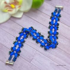 a blue beaded necklace on a wooden table with flowers in the background and text, starlight gems bracelet pattern