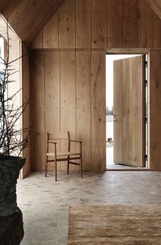 a room with wood paneling and a chair in the corner next to an open door