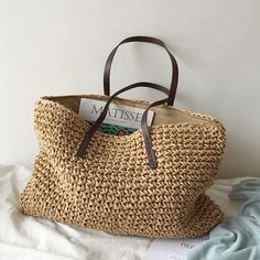 a straw bag sitting on top of a bed next to a book and magazine holder