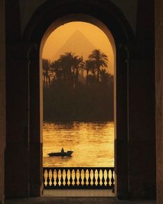 a person in a small boat on the water at sunset with an arch leading to it