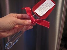 a person is holding a red ribbon in front of an icebox that has a note attached to it