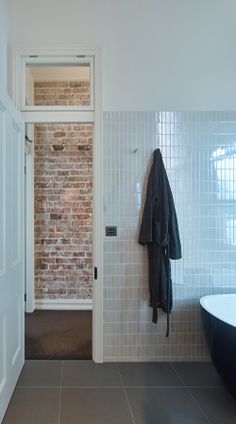 a bathroom with a brick wall and black bathtub next to a white door that leads to a walk in shower