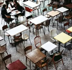 many tables and chairs are lined up in a room with people sitting at their desks