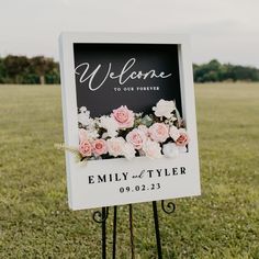 a welcome sign with flowers on it in the grass