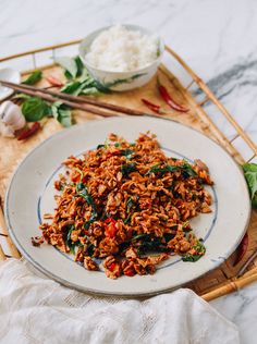 a white plate topped with rice and meat next to chopsticks on a table