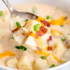 a spoon full of potato soup with bacon and green onions on the side, in a white bowl