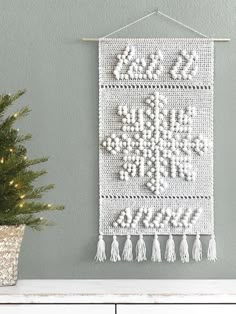 a white wall hanging next to a christmas tree