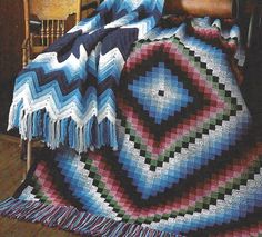 a crocheted afghan is draped on a chair with a wooden table in the background