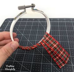 a hand holding a piece of fabric with a bow on it and sewing needles in the background