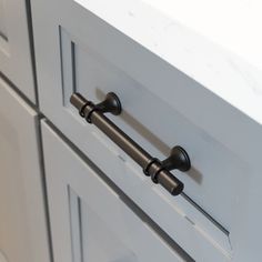 a close up view of the handles on a kitchen cabinet with white countertops and drawers