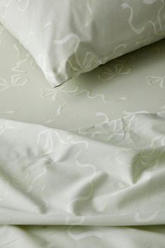 an unmade bed with white sheets and pillows