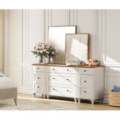 a white dresser with flowers and a mirror