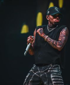 a man with tattoos holding a microphone on stage