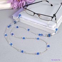 Fun and sporty for you weekend wear, our clear eyeglass chain feature blue beads for a hint of color. You will never have to worry about misplacing your eyeglasses again. Makes for a great gift for yourself or a loved one. Rubber loops adjust to fit most glasses frames.   🦉Product Details:  * Approx. Length - 31 1/2 in (including rubber loops) * Chain Weight: 1.5 oz * Bead Color(s): Blue, White * Metal Color: Silver-tone * Material: Glass Beads * Closure: Lobster Claw Clasps and Rubber Loop Ends * Product ID: G241 🎁 Gift packaging available at Checkout ($4.00 USD) - See last image   🦉NOTES: * Not recommended for young children! * The lobster clasps make replacement of the rubber loops easy if they break. * All measurements and weights are approximate and may vary slightly from the liste Elegant Blue Glass Glasses Chains, Handmade Blue Glass Glasses Chains, Elegant Adjustable Blue Glasses Chains, Elegant Blue Adjustable Glasses Chains, Blue Beaded Chain Glasses Chains With Round Beads, Blue Beaded Glass Glasses Chains, Blue Beaded Glasses Chains, Blue Glasses Chains With Round Beaded Chain, Trendy Blue Glass Glasses Chains