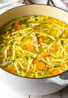 a pot filled with chicken noodle soup on top of a table