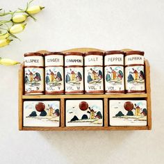 a wooden box filled with different types of salt and pepper shakers next to yellow flowers