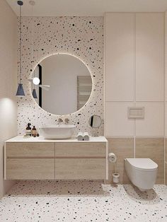 a bathroom with a large round mirror above the sink and a white toilet in front of it