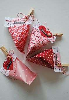 four red and white heart shaped bags with clothes pegs attached to them, tied together