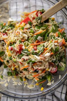 a salad in a glass bowl with a wooden spoon