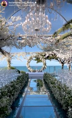 an outdoor ceremony setup with white flowers and chandelier hanging from it's ceiling