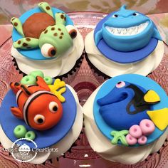 three cupcakes decorated with fondant sea creatures on top of a glass plate