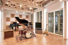 a living room filled with lots of furniture and musical instruments on top of hard wood flooring