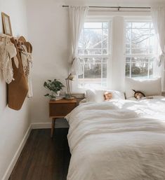 a white bed sitting in a bedroom next to a window