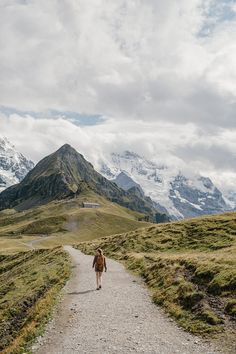 a person walking down a dirt road in the mountains