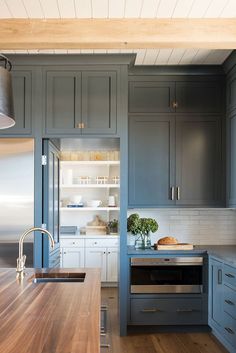 a large kitchen with blue cabinets and wood flooring on the countertops, along with an island