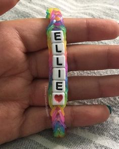 a person holding a colorful bracelet with the word love spelled on it in white letters