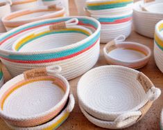 many baskets are lined up on the table with tags attached to each one and they have different colors