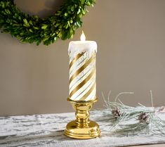 a candle that is on top of a table next to a wreath and pine cones