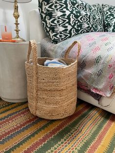 a basket sitting on top of a bed next to a lamp and pillow in a room