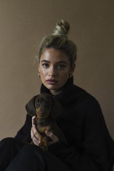 a woman is holding a small dog in her lap and looking at the camera with an intense look on her face