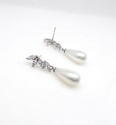 Tarnish resistant white gold plated brass half flower post earrings (posts are sterling silver) decorated with luxury cubic zirconia and high aaa quality off white (pale light cream) teardrop shell pearls. Size:3.8.cm x .8 cm White Cubic Zirconia Teardrop Pearl Earrings, White Teardrop Pearl Earrings With Cubic Zirconia, White Pearl Drop Teardrop Earrings With Cubic Zirconia, Silver Pearl Bridal Earrings Pear-shaped, Silver Pear-shaped Pearl Bridal Earrings, White Cubic Zirconia Teardrop Earrings With Pearl Drop, Pear-shaped Pearl Bridal Earrings In Silver, Pearl White Teardrop Pearl Earrings With Cubic Zirconia, Teardrop Pearl White Cubic Zirconia Earrings