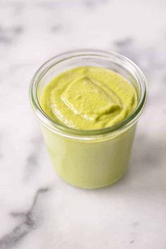 a jar filled with green sauce on top of a marble counter