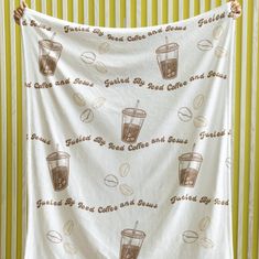 a tea towel hanging on a wall with coffee cups and drinks printed on the fabric