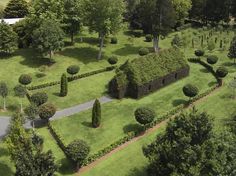 an aerial view of a lush green field with trees and bushes in the center, surrounded by hedges