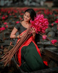 a woman sitting on the ground holding flowers