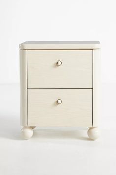 a white wooden cabinet with two drawers on one side and three knobs on the other