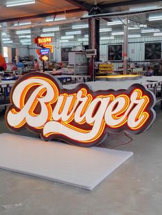 a large neon sign that says burger on it's side in an industrial setting