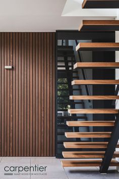 a wooden stair case in front of a glass door and stairs with wood slats