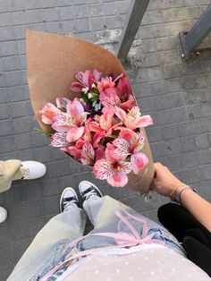 a person holding a bouquet of pink flowers